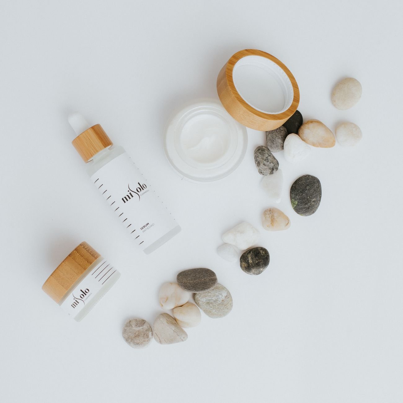 Flat lay of high-end skincare products with stones on a white background.